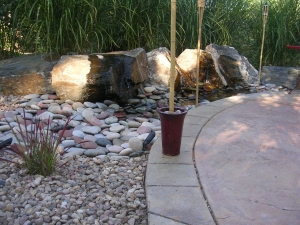 Decorative garden with large rocks and a concrete pathway under natural sunlight.